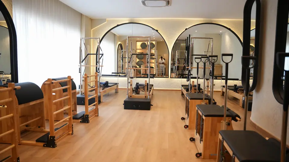 Sala de Pilates Reformer de Balans Studio con espejos en arco, luz cálida y equipos de madera